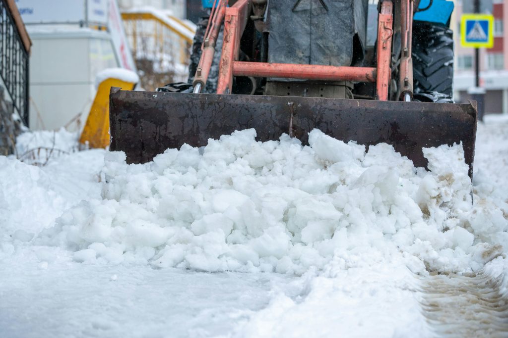 Snow plow clearing driveway during winter storm in Sarnia Ontario